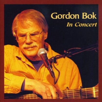 Gordon lit by stage lighting, singing into a mic and playing guitar,